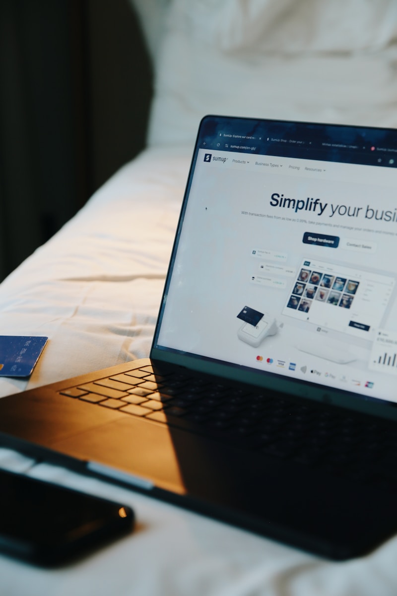 Laptop, phone, and card on a bed.
